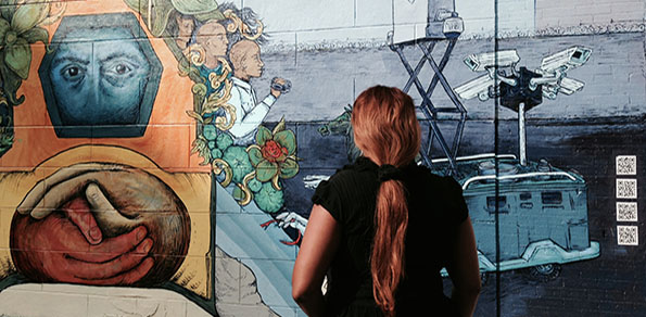 A woman stops to gaze at the new mural on Brook Ave (Rosalind Adams/ The Bronx Ink)