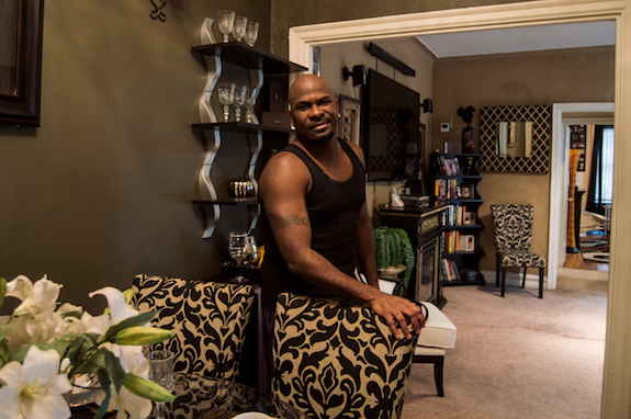 Damon Flowers posed in his apartment, which he renovated himself. He said when he moved in, the floors were linoleum and the kitchen smelled like gas.