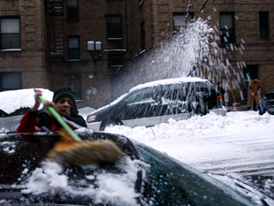 People play and clean during a snowstorm near 231st Street in Bronx, NY on February 10, 2010.